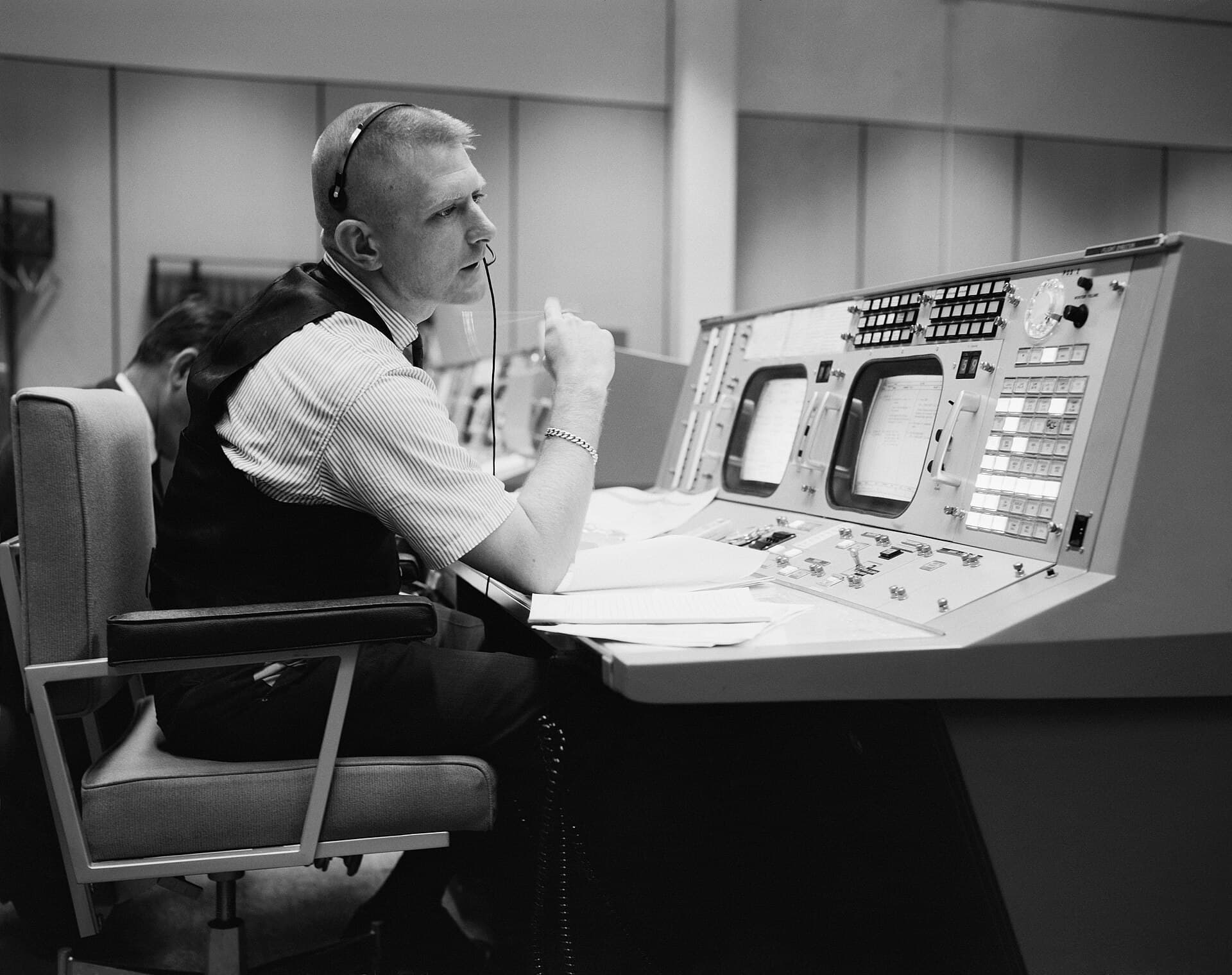 A flight director surrounded by instruments at a mission control console.